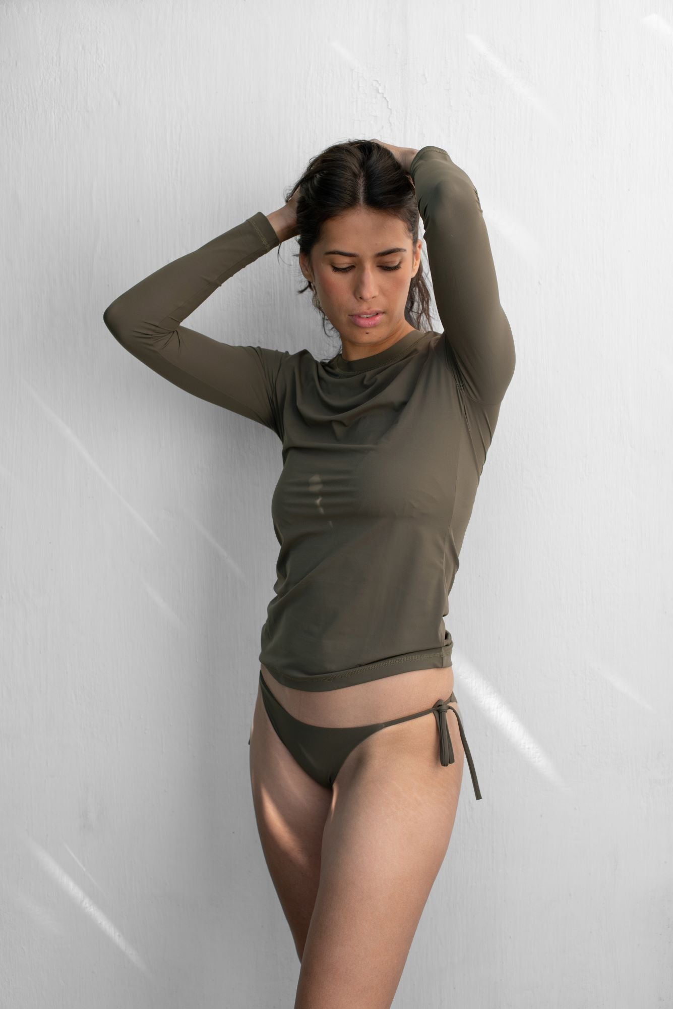 Woman wearing a olive SPF50+ rashguard with matching bikini bottom